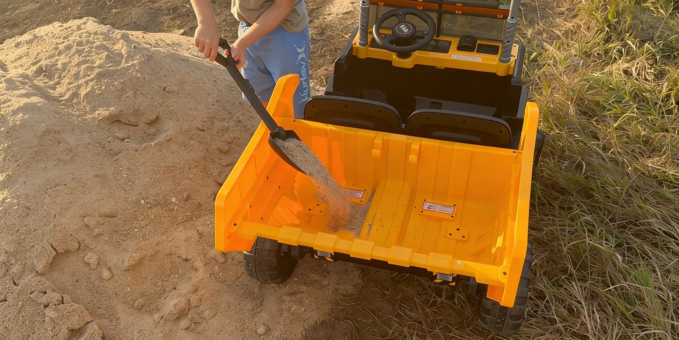 Small orange utility vehicle with a shovel in a sandy area