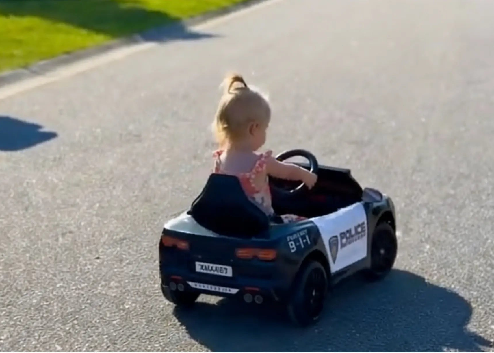 Child in a toy police car on a road