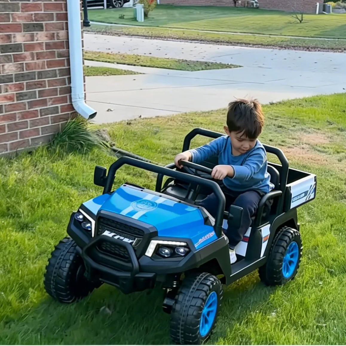 Child playing with a blue toy truck on a grassy area next to a brick building.