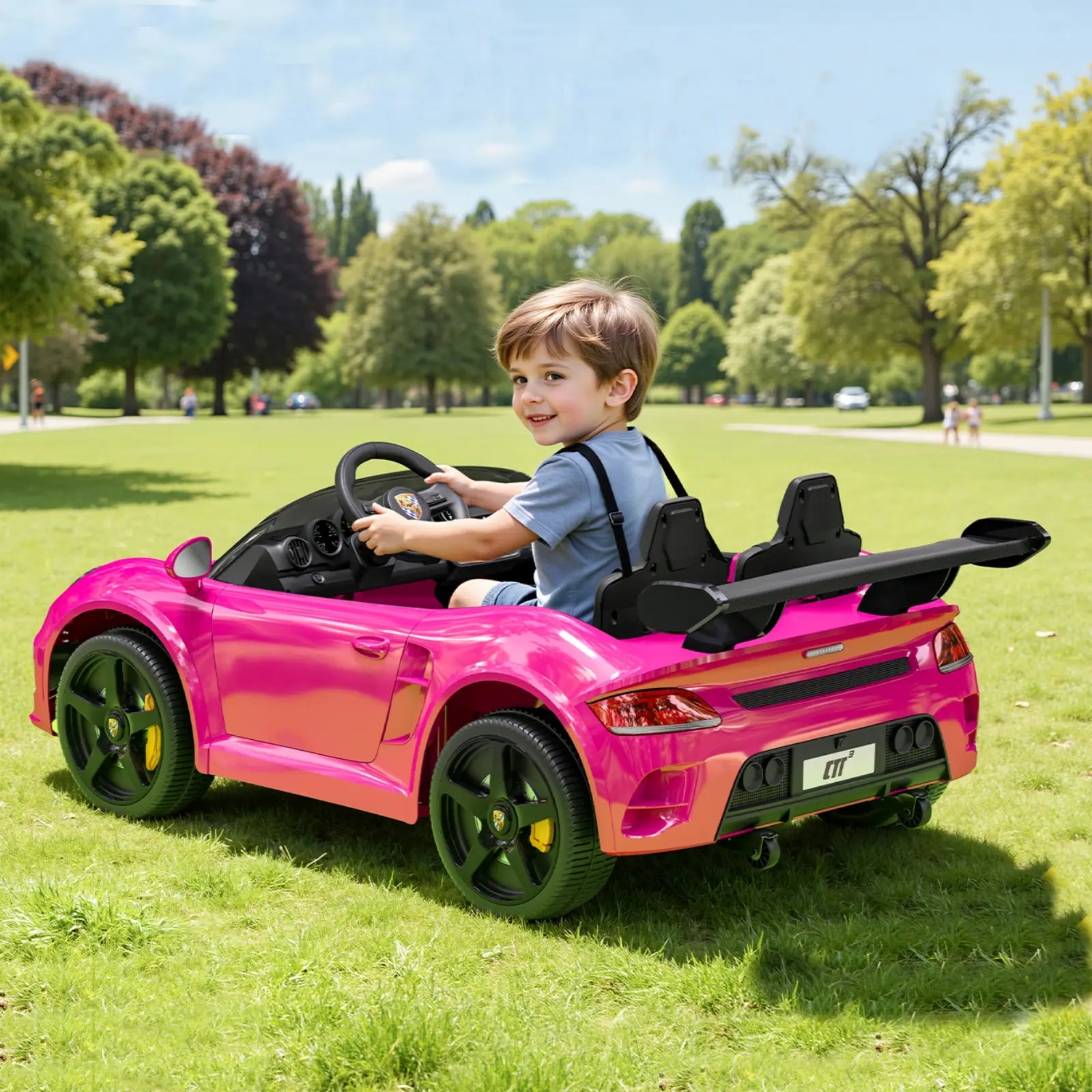 Child driving a pink sports car in a park